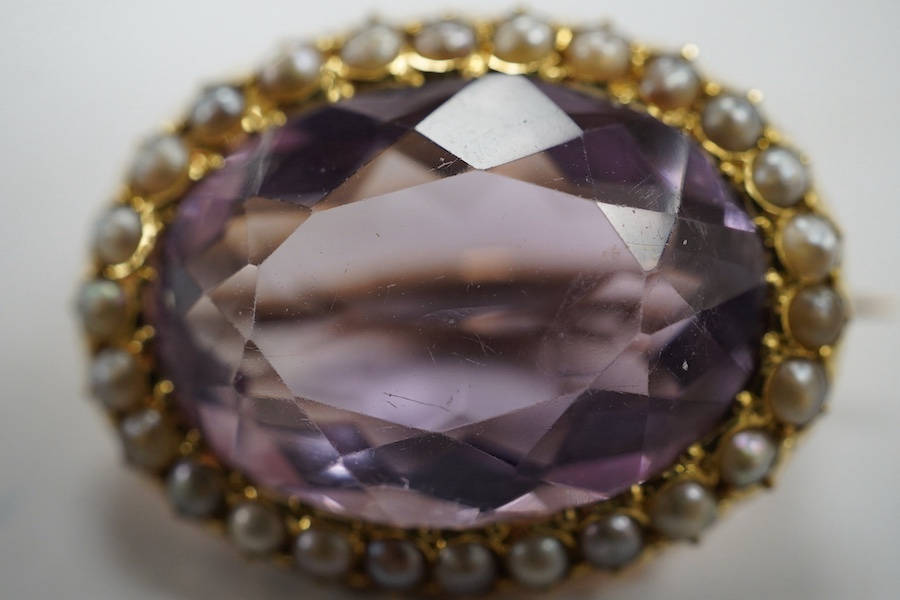 An Edwardian 15ct, amethyst and split pearl cluster set oval brooch, 23mm, gross weight 5 grams. Condition - good